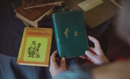 First edition Winne-the-Pooh being held with another book in background. Credit, UQ